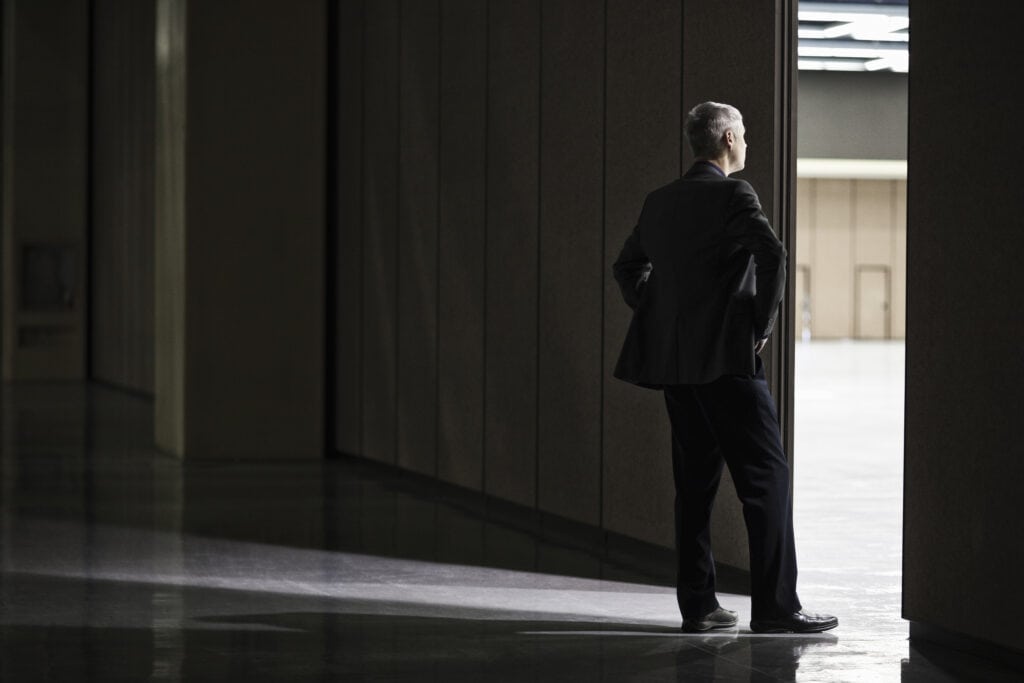 IT Continuity and exit plan. An image of a businessman standing in a large warehouse doorway, representing the enormity of making a continuity plan.