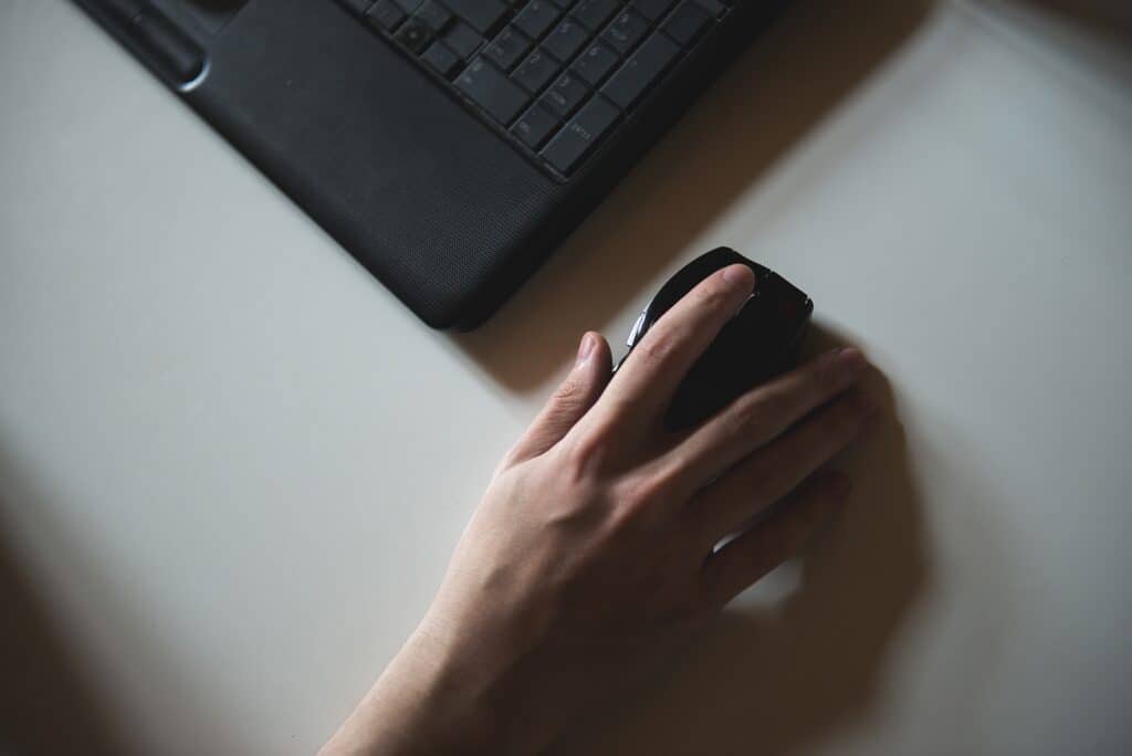 Easy Phishing Simulations Create False Confidence - hand on a mouse next to a laptop | Virtuas.com